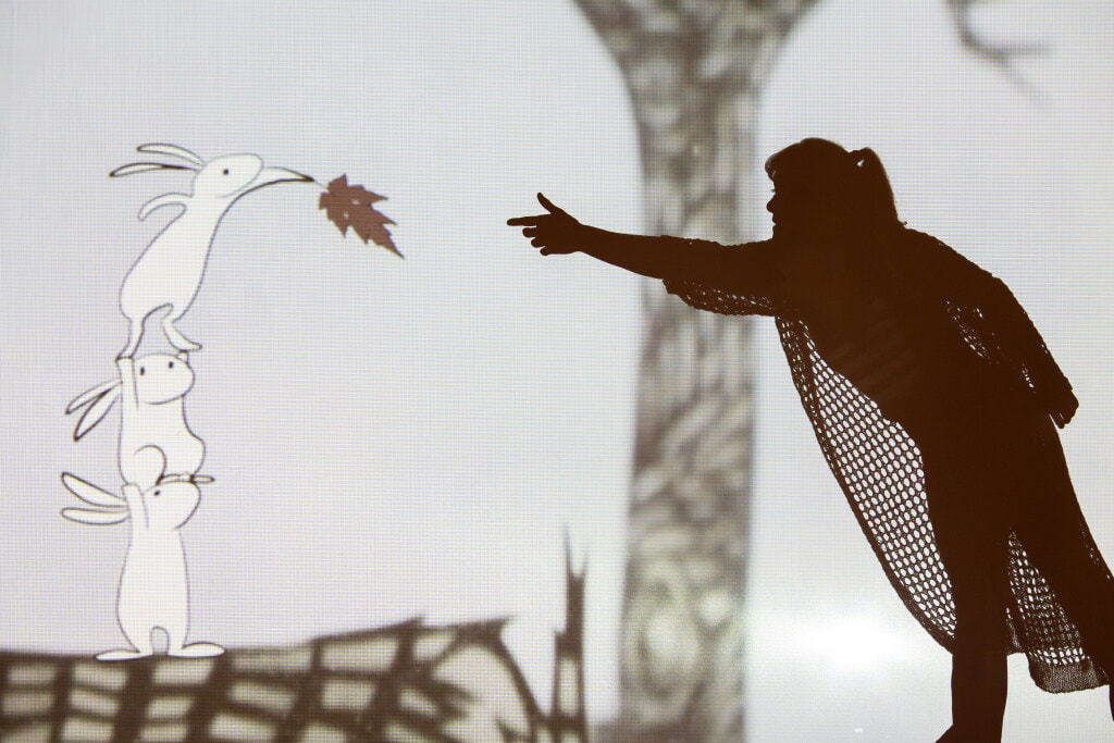 Abigail Baird performing aerial acrobatics in front of projected animation