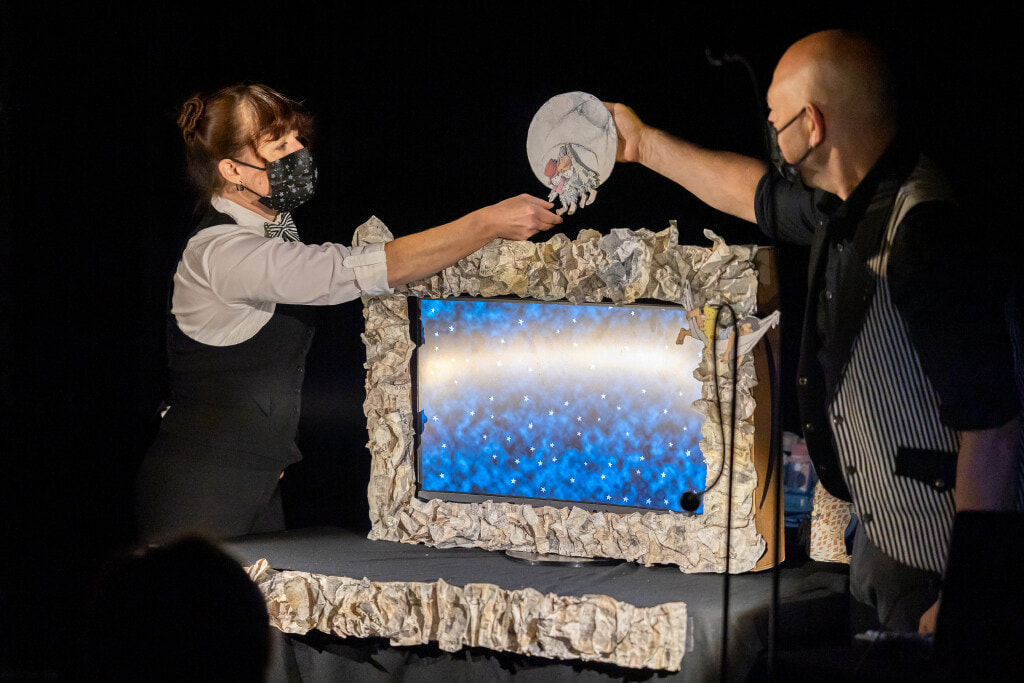 A scene blending hand-drawn animation and live aerial performance