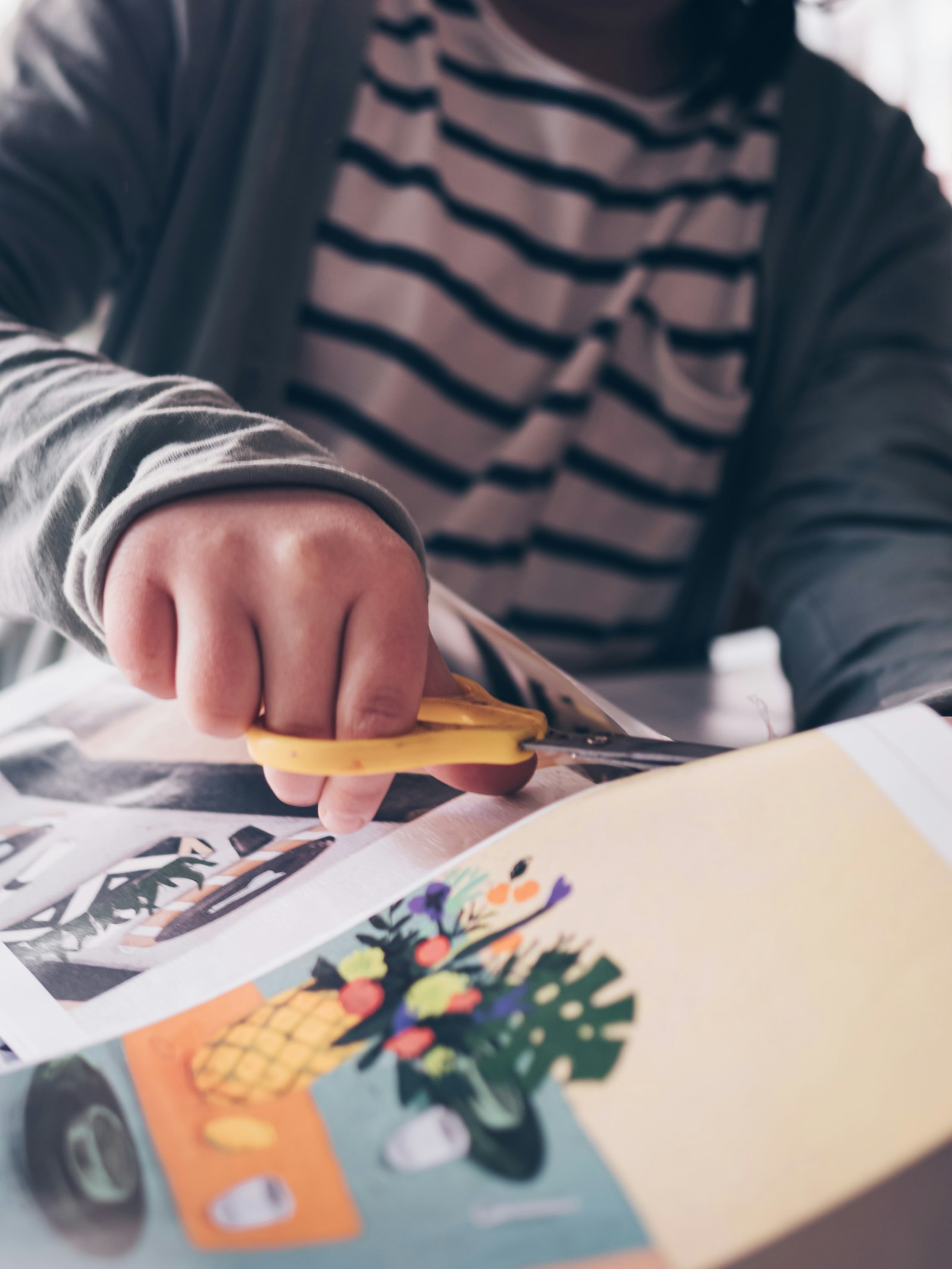 A child cutting out a colorful paper craft with scissors
