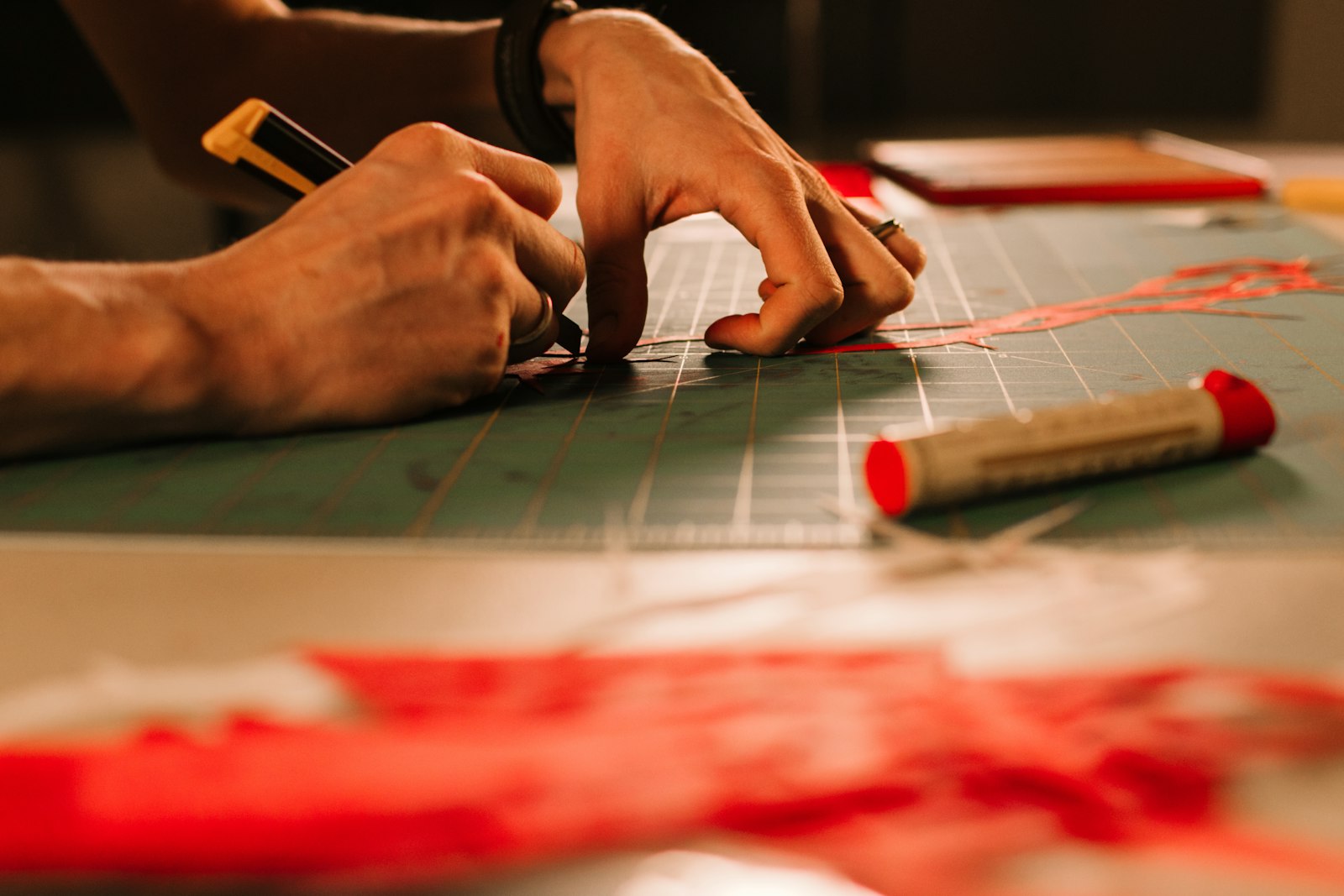 Hands cutting paper with a craft knife on a green cutting mat